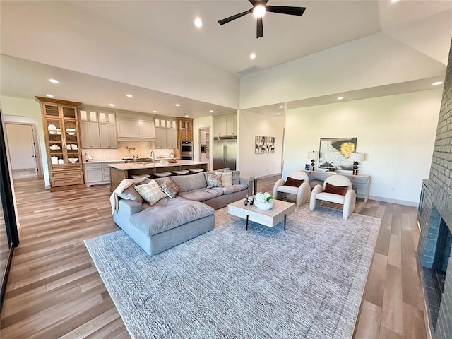 3320 Somerset Farms Rd, Newalla, OK 74857 - living area with a fireplace, a towering ceiling, recessed lighting, a ceiling fan, and light wood finished floors