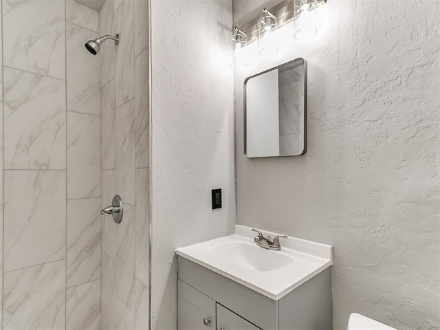 3522 SW 39th St, Oklahoma City, OK 73119 - bathroom with a tile shower, vanity, toilet, and a textured wall