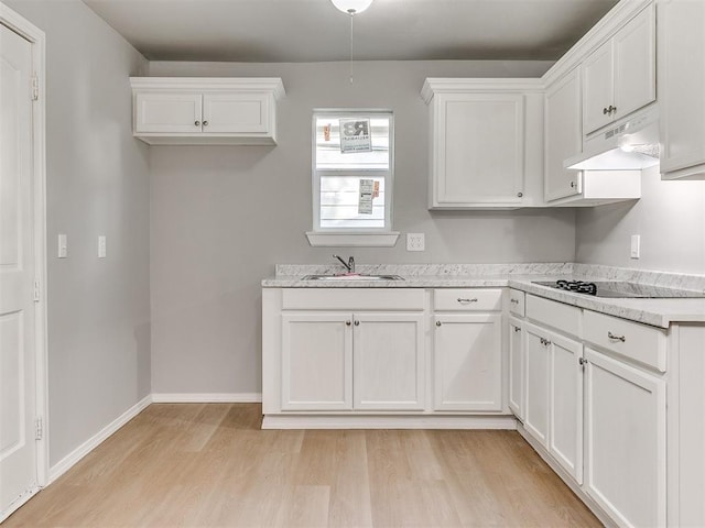 3522 SW 39th St, Oklahoma City, OK 73119 - kitchen featuring a sink, light wood-style floors, under cabinet range hood, black electric stovetop, and white cabinetry