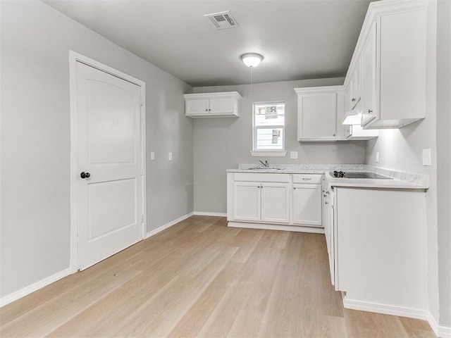 3522 SW 39th St, Oklahoma City, OK 73119 - kitchen featuring a sink, light wood-style floors, white cabinets, light countertops, and baseboards