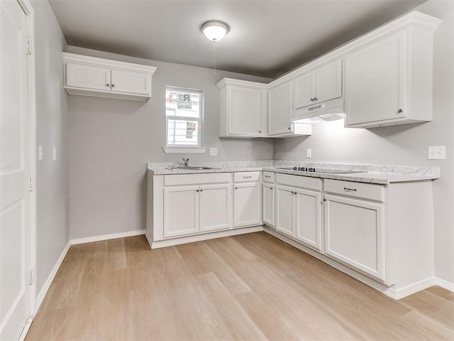 3522 SW 39th St, Oklahoma City, OK 73119 - kitchen with black electric stovetop, light wood finished floors, under cabinet range hood, a sink, and white cabinets