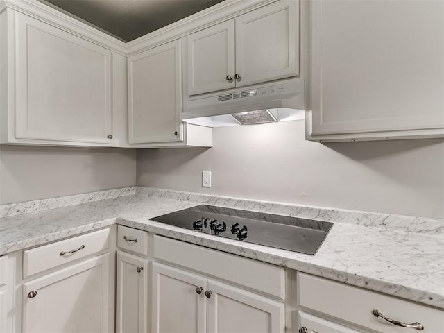 3522 SW 39th St, Oklahoma City, OK 73119 - kitchen featuring under cabinet range hood, black electric stovetop, light countertops, and white cabinetry