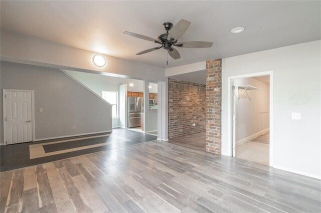 1217 SW 18th St, Oklahoma City, OK 73109 - unfurnished living room featuring a ceiling fan, light wood-type flooring, baseboards, and brick wall