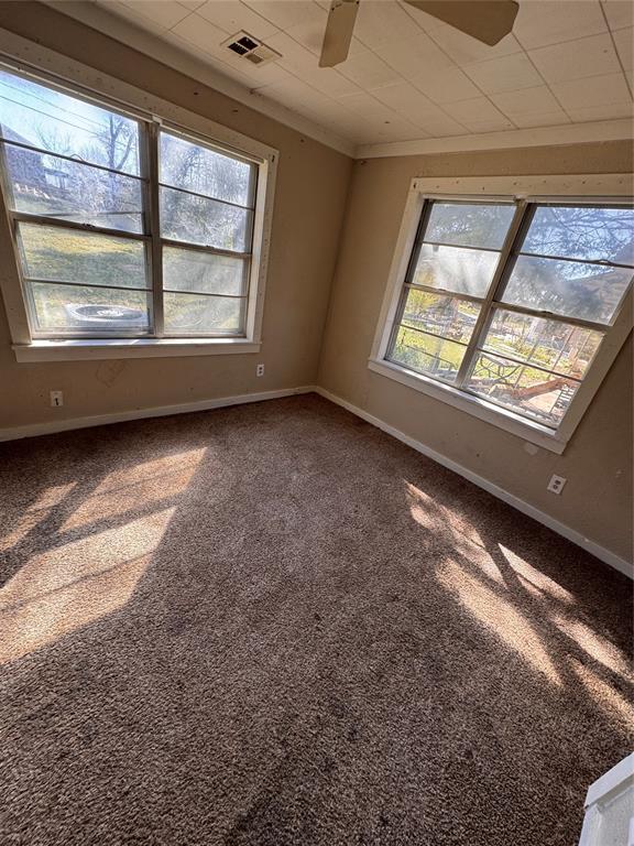 424 Jefferson St, Seminole, OK 74868 - spare room featuring ceiling fan, baseboards, carpet floors, and crown molding