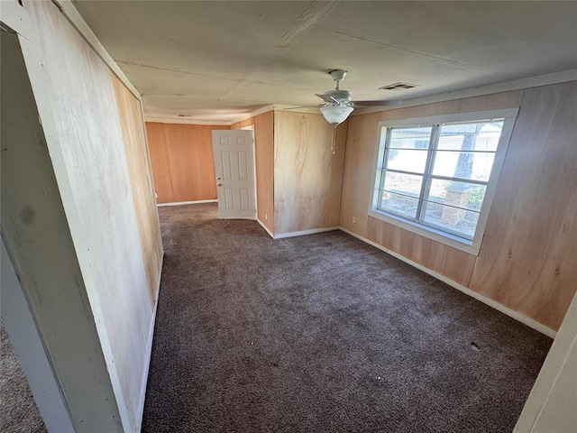 424 Jefferson St, Seminole, OK 74868 - empty room featuring carpet, wooden walls, baseboards, and a ceiling fan