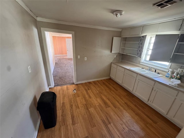 424 Jefferson St, Seminole, OK 74868 - kitchen with a sink, open shelves, ornamental molding, white cabinets, and light wood-type flooring