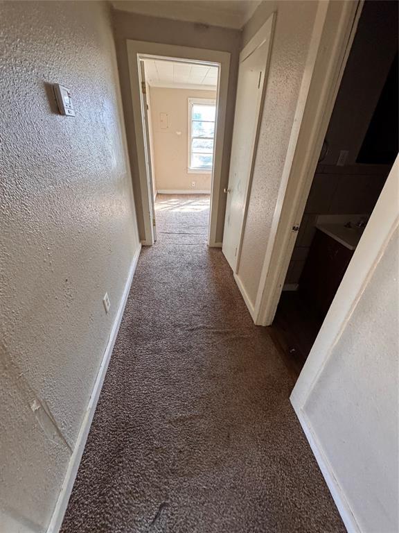 424 Jefferson St, Seminole, OK 74868 - hall featuring carpet, a textured wall, and baseboards