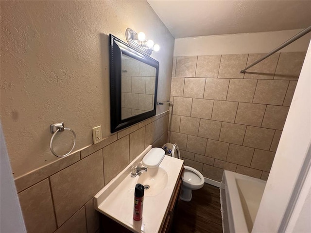 424 Jefferson St, Seminole, OK 74868 - full bathroom with toilet, vanity, tile walls, wood finished floors, and a textured wall