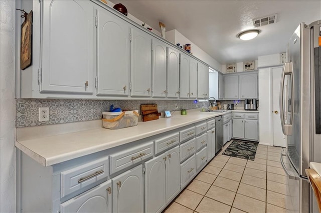 912 SW 4th Pl, Moore, OK 73160 - kitchen featuring appliances with stainless steel finishes, light tile patterned floors, backsplash, a sink, and light countertops