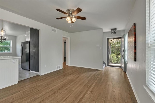615 Ridgecrest Rd, Edmond, OK 73013 - unfurnished living room with light wood-type flooring, ceiling fan, baseboards, and a chandelier
