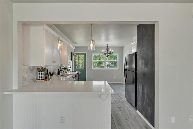 615 Ridgecrest Rd, Edmond, OK 73013 - kitchen with freestanding refrigerator, light countertops, decorative backsplash, white cabinets, and a peninsula