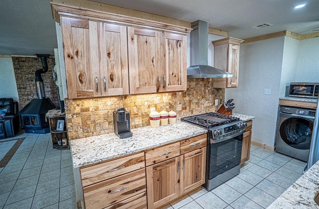 106049 N 3855-1 Rd, Weleetka, OK 74880 - kitchen featuring washer / dryer, appliances with stainless steel finishes, wall chimney exhaust hood, a wood stove, and light tile patterned floors