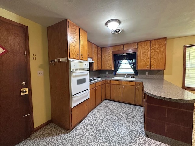 811 N Broadway St, Broken Bow, OK 74728 - kitchen with a warming drawer, white appliances, a peninsula, brown cabinets, and ventilation hood