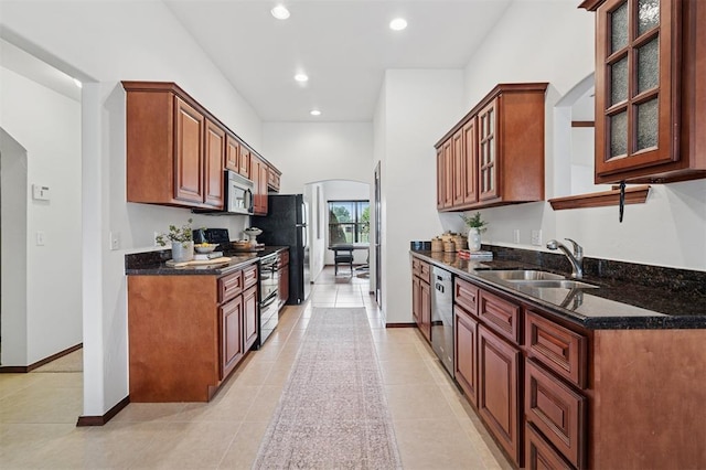709 S Greengate Dr, Yukon, OK 73099 - kitchen with stainless steel appliances, arched walkways, light tile patterned floors, recessed lighting, and glass insert cabinets
