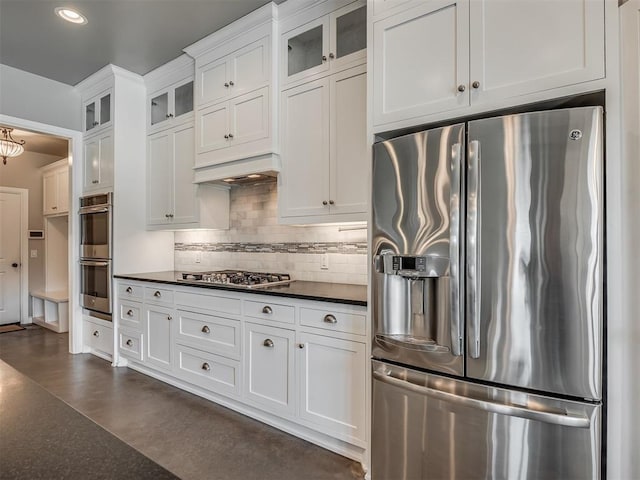 5021 SE 12th Ave, Washington, OK 73093 - kitchen with stainless steel appliances, dark countertops, tasteful backsplash, white cabinetry, and glass insert cabinets