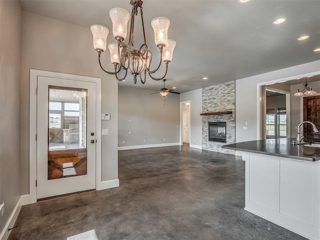5021 SE 12th Ave, Washington, OK 73093 - kitchen featuring a chandelier, concrete floors, a stone fireplace, dark countertops, and pendant lighting
