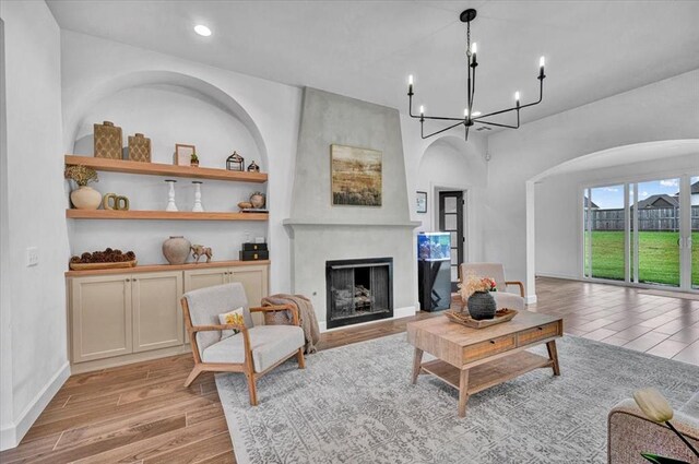 1049 Dorsi Way, Newcastle, OK 73065 - living area with arched walkways, light wood finished floors, a fireplace, a chandelier, and recessed lighting