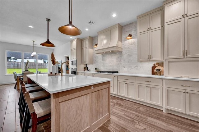 1049 Dorsi Way, Newcastle, OK 73065 - kitchen featuring black gas stovetop, custom exhaust hood, oven, decorative backsplash, and a kitchen breakfast bar