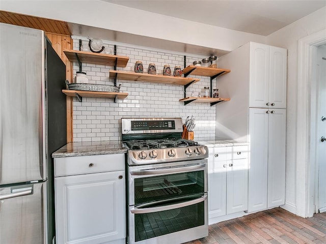 2647 NW 24th St, Oklahoma City, OK 73107 - kitchen with stainless steel appliances, open shelves, tasteful backsplash, light stone counters, and white cabinets