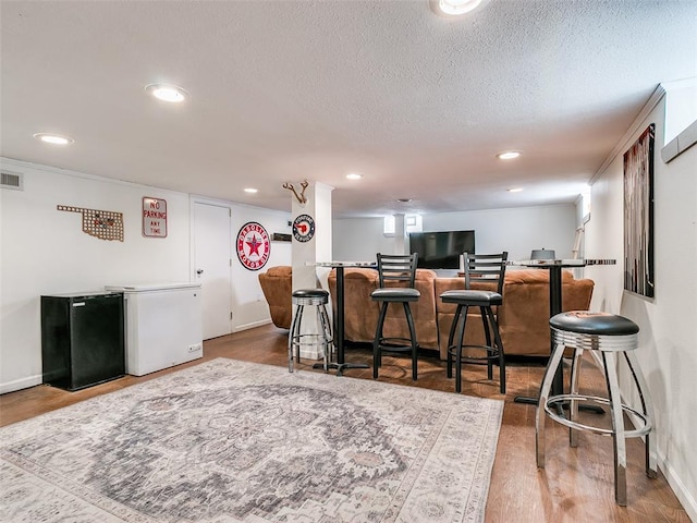 2647 NW 24th St, Oklahoma City, OK 73107 - kitchen with refrigerator, freestanding refrigerator, a breakfast bar, a textured ceiling, and recessed lighting