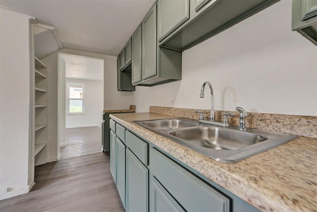 3808 S Hudson Ave, Oklahoma City, OK 73109 - kitchen featuring a sink, light wood-style floors, light countertops, baseboards, and green cabinetry
