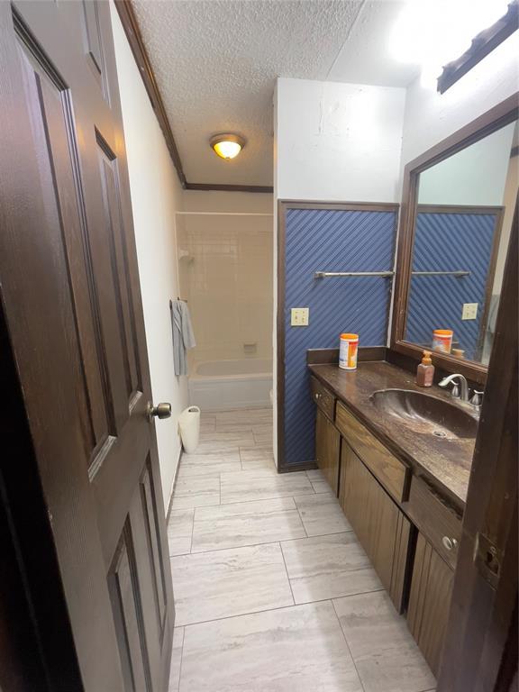 8228 NW 90th Ter, Oklahoma City, OK 73132 - bathroom featuring vanity, a textured ceiling, and shower / bath combination
