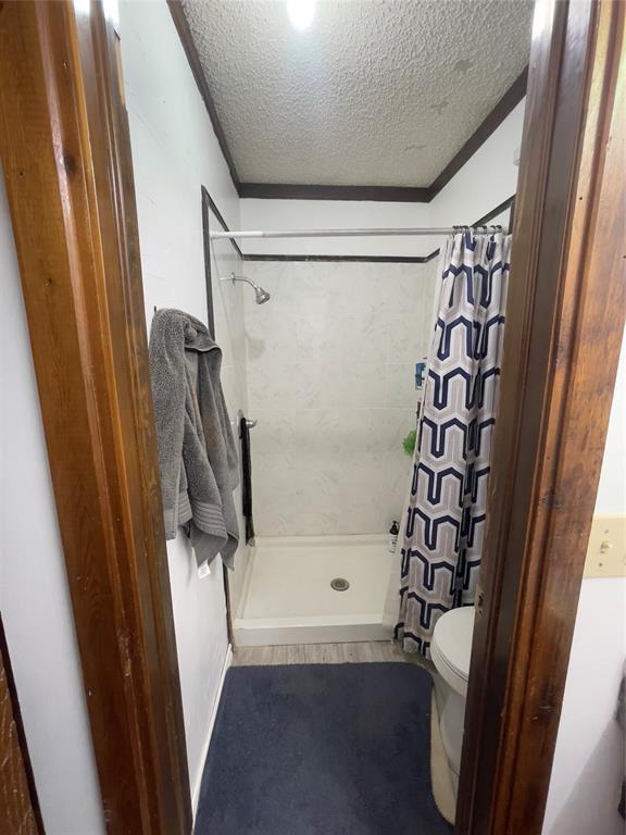 8228 NW 90th Ter, Oklahoma City, OK 73132 - full bathroom featuring a textured ceiling, a stall shower, and crown molding