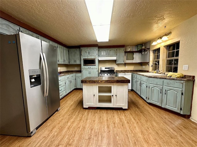 20973 US Highway 62, Altus, OK 73521 - kitchen featuring stainless steel appliances, a sink, a textured ceiling, dark countertops, and light wood finished floors