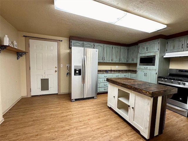 20973 US Highway 62, Altus, OK 73521 - kitchen featuring stainless steel appliances, under cabinet range hood, a textured ceiling, wood counters, and light wood-type flooring