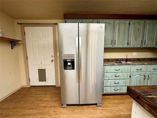 20973 US Highway 62, Altus, OK 73521 - kitchen featuring stainless steel fridge, dark countertops, light wood finished floors, and green cabinets
