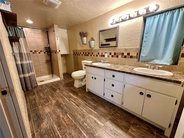 20973 US Highway 62, Altus, OK 73521 - full bathroom featuring a textured ceiling, double vanity, toilet, tiled shower, and wood finished floors