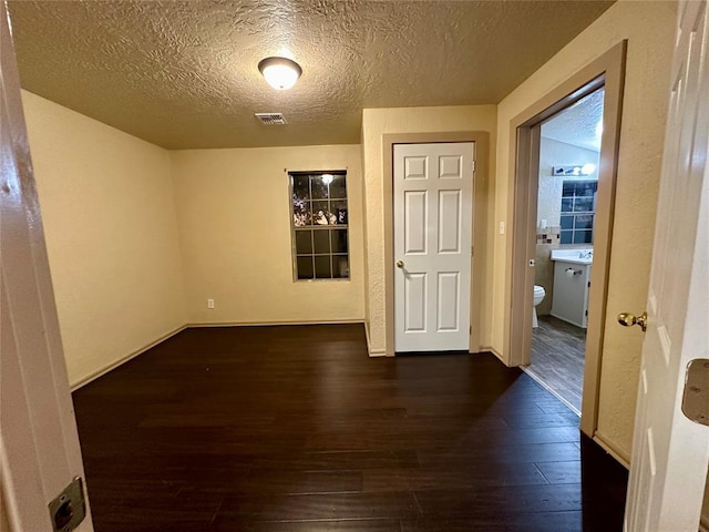 20973 US Highway 62, Altus, OK 73521 - empty room featuring dark wood-style flooring, a textured ceiling, and baseboards