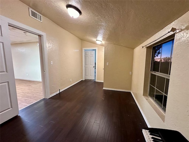 20973 US Highway 62, Altus, OK 73521 - unfurnished room with vaulted ceiling, a textured ceiling, a textured wall, wood finished floors, and baseboards