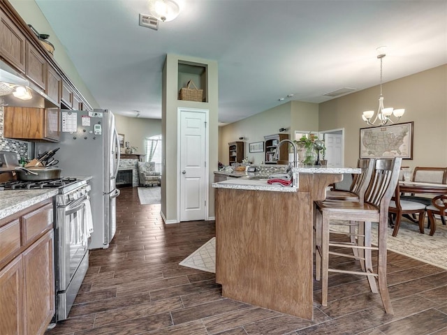 1816 Concord Pl, Norman, OK 73071 - kitchen with gas stove, dark wood-style floors, a chandelier, a kitchen island with sink, and a breakfast bar