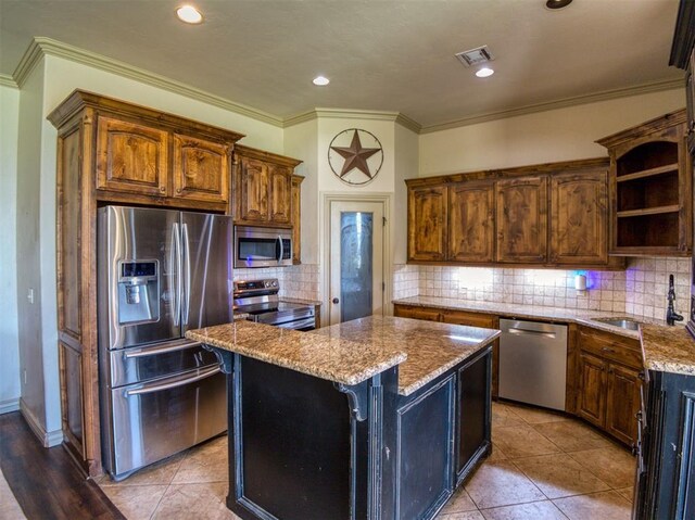 866 County St Unit 2922, Tuttle, OK 73089 - kitchen featuring stainless steel appliances, a sink, a kitchen island, open shelves, and light stone counters