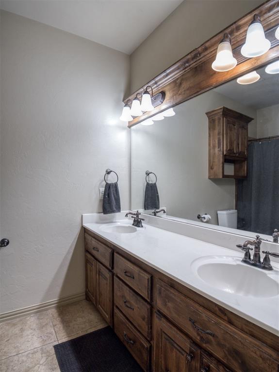 866 County St Unit 2922, Tuttle, OK 73089 - bathroom with baseboards, double vanity, toilet, and a shower with curtain