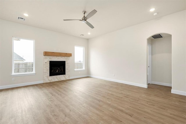 1208 Ariana St, Shawnee, OK 74804 - unfurnished living room featuring light wood finished floors, arched walkways, baseboards, a ceiling fan, and a fireplace