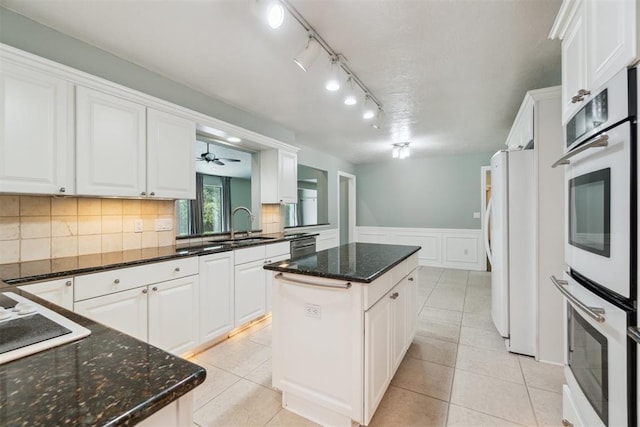 4208 Briarcrest St, Norman, OK 73072 - kitchen featuring a kitchen island, white cabinets, white appliances, wainscoting, and dark stone countertops