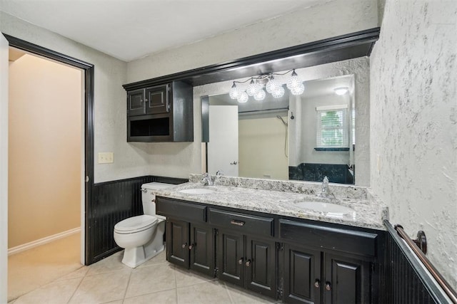 4208 Briarcrest St, Norman, OK 73072 - bathroom featuring double vanity, tile patterned floors, a textured wall, and a wainscoted wall
