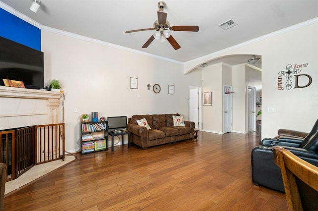 2365 Turtlewood River Rd, Midwest City, OK 73130 - living room featuring a ceiling fan, wood finished floors, crown molding, arched walkways, and a tiled fireplace