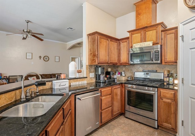 2365 Turtlewood River Rd, Midwest City, OK 73130 - kitchen with stainless steel appliances, a sink, ceiling fan, brown cabinets, and tasteful backsplash