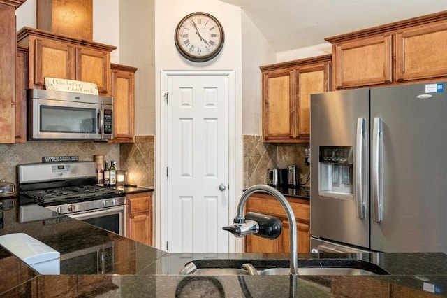 2365 Turtlewood River Rd, Midwest City, OK 73130 - kitchen featuring appliances with stainless steel finishes, brown cabinets, decorative backsplash, a sink, and dark stone countertops