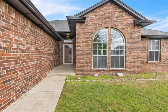 2309 NW 157th Ter, Edmond, OK 73013 - doorway to property with roof with shingles, a lawn, and brick siding