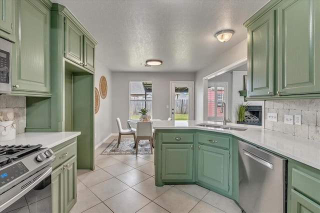 2309 NW 157th Ter, Edmond, OK 73013 - kitchen featuring green cabinets, appliances with stainless steel finishes, a sink, light countertops, and backsplash