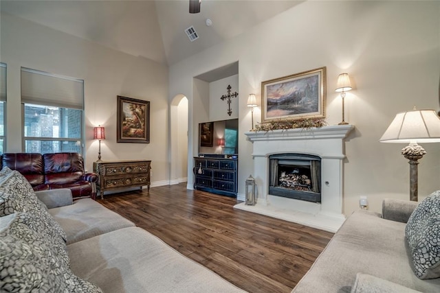 2717 Cordgrass Ln, Edmond, OK 73013 - living room with wood finished floors, arched walkways, a fireplace with raised hearth, baseboards, and high vaulted ceiling