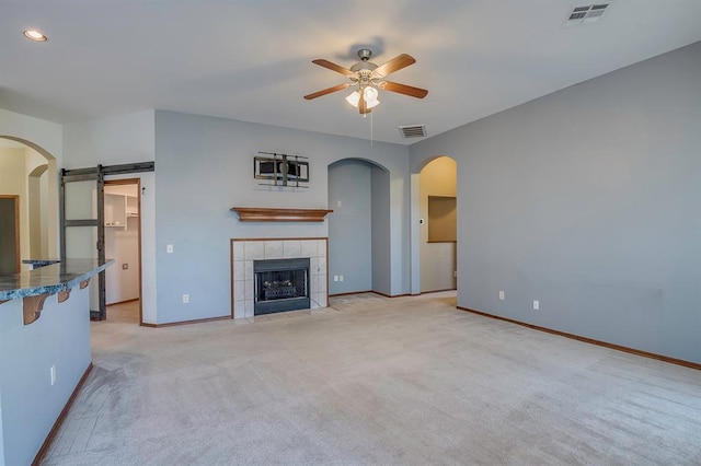 832 Elm Creek Dr, Moore, OK 73160 - unfurnished living room featuring a ceiling fan, light colored carpet, baseboards, a barn door, and arched walkways