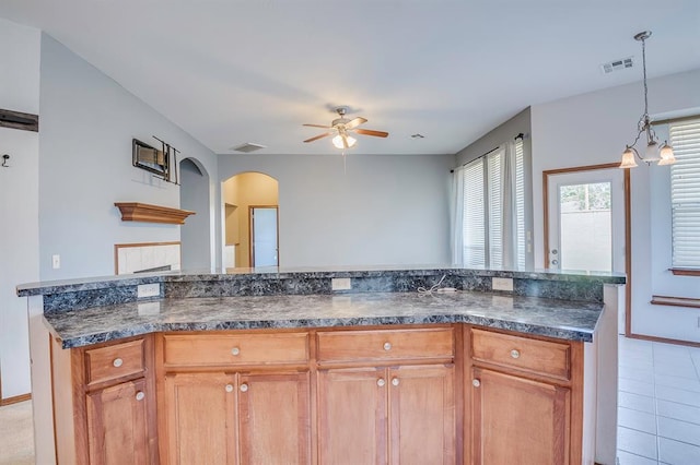 832 Elm Creek Dr, Moore, OK 73160 - kitchen with ceiling fan, arched walkways, baseboards, decorative light fixtures, and brown cabinetry