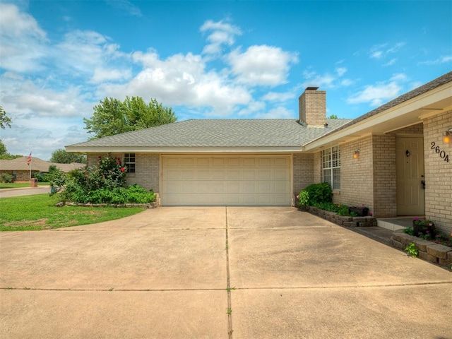 2604 Jeannes Trl, Edmond, OK 73012 - view of front of home featuring concrete driveway, a garage, brick siding, and a chimney