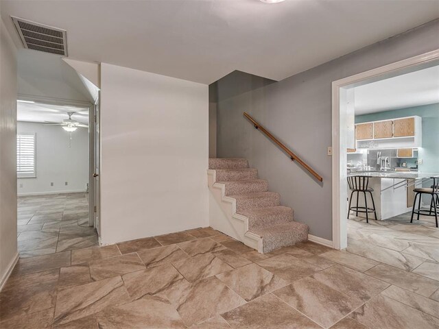 2604 Jeannes Trl, Edmond, OK 73012 - stairs featuring stone tile floors, a ceiling fan, and baseboards