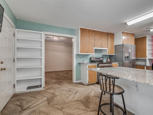 2604 Jeannes Trl, Edmond, OK 73012 - kitchen featuring appliances with stainless steel finishes, a breakfast bar area, and light stone counters